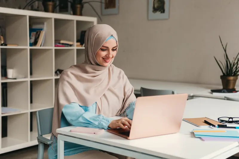 امرأة تعمل على حاسوب محمول في مكتب مضيء